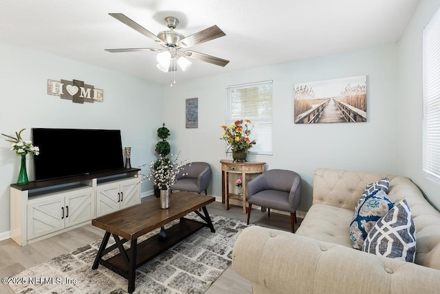 living area with light wood-style floors, ceiling fan, and baseboards