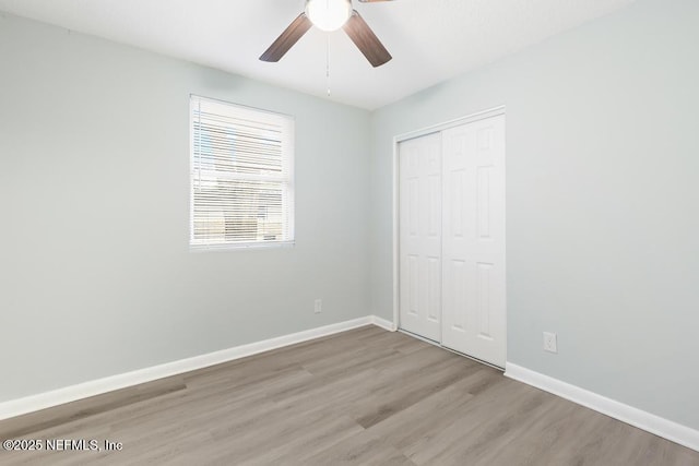 unfurnished bedroom with light wood finished floors, ceiling fan, baseboards, and a closet