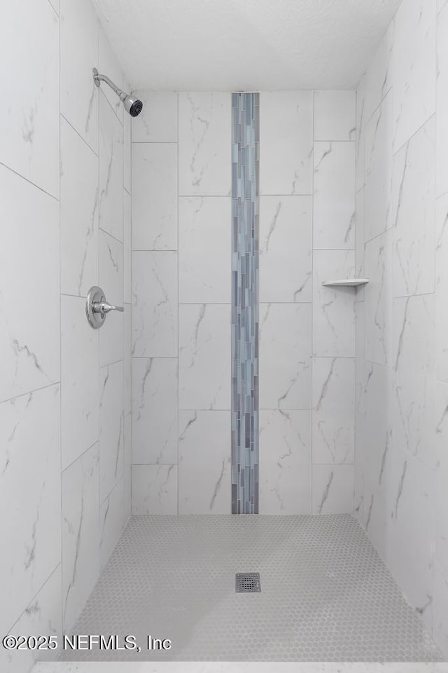 bathroom with a textured ceiling and a tile shower