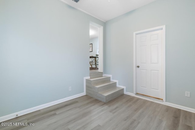 interior space featuring light wood-type flooring, stairway, visible vents, and baseboards