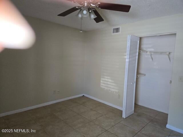 unfurnished bedroom featuring a textured ceiling, a ceiling fan, visible vents, baseboards, and a closet