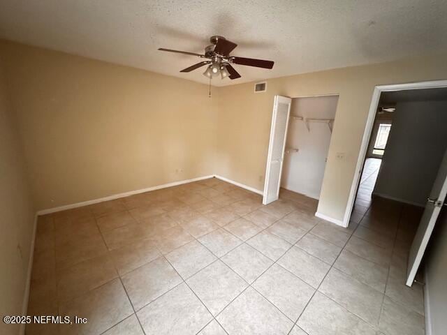 unfurnished bedroom featuring light tile patterned floors, a closet, visible vents, a textured ceiling, and baseboards