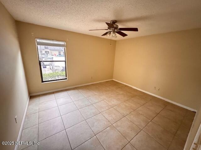 unfurnished room with a textured ceiling, a ceiling fan, and baseboards