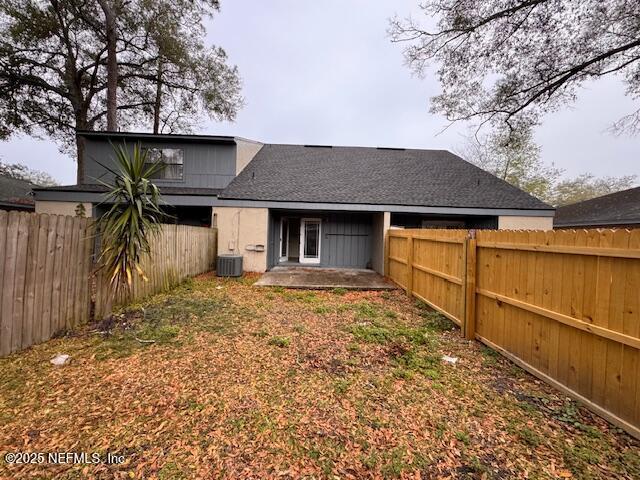 rear view of house featuring a fenced backyard, a patio, central AC, and roof with shingles