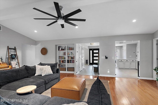 living area with light wood finished floors, a ceiling fan, baseboards, and vaulted ceiling