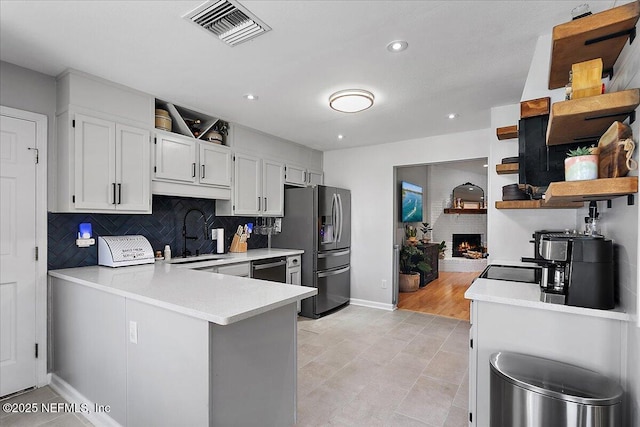 kitchen with a sink, visible vents, stainless steel fridge with ice dispenser, and light countertops