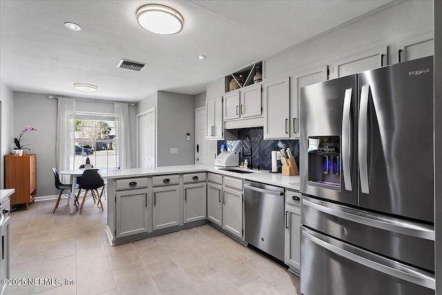 kitchen with visible vents, light countertops, gray cabinets, a peninsula, and stainless steel appliances