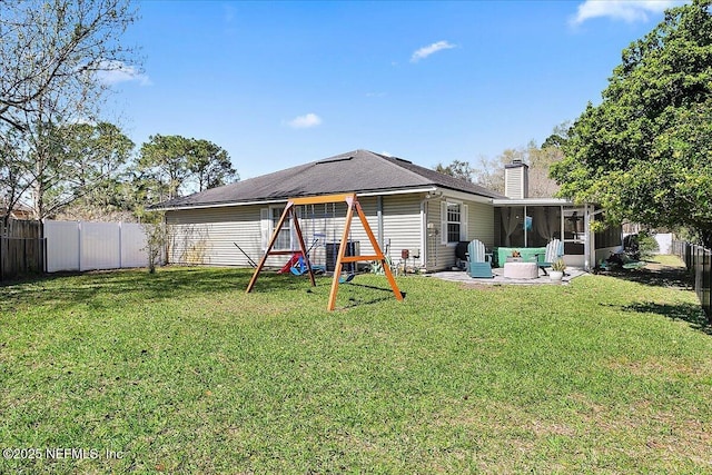 back of property with a yard, a playground, a fenced backyard, and a sunroom