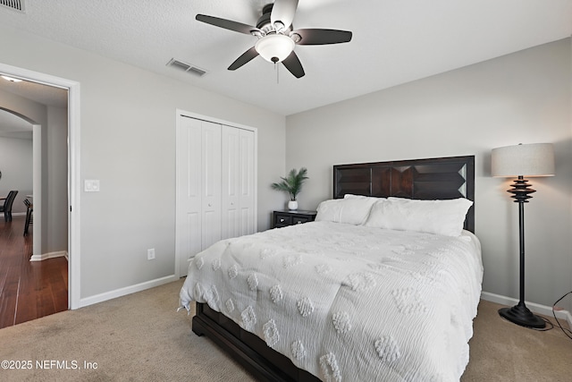 bedroom featuring baseboards, visible vents, arched walkways, carpet, and a closet