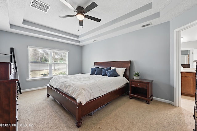 bedroom featuring light colored carpet, a tray ceiling, visible vents, and baseboards