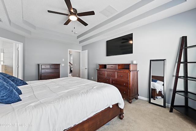 bedroom featuring light carpet, baseboards, visible vents, a ceiling fan, and a tray ceiling