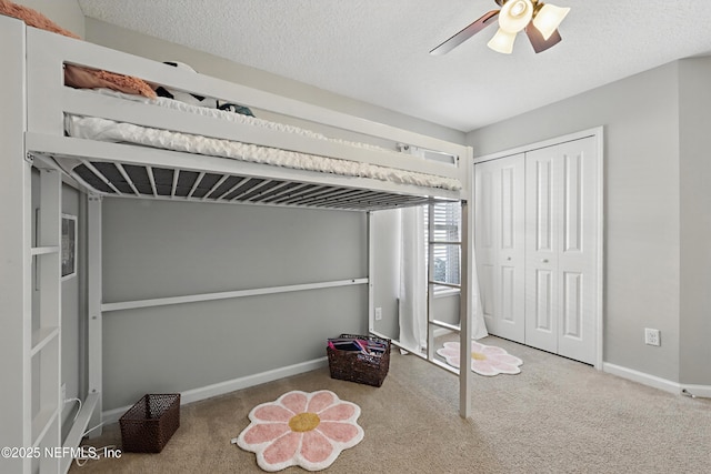 unfurnished bedroom featuring baseboards, a ceiling fan, a textured ceiling, carpet flooring, and a closet