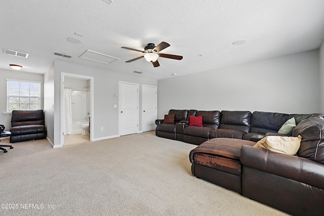 carpeted living room with baseboards, a textured ceiling, visible vents, and attic access