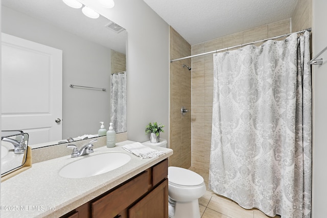 bathroom with a textured ceiling, toilet, vanity, visible vents, and a tile shower