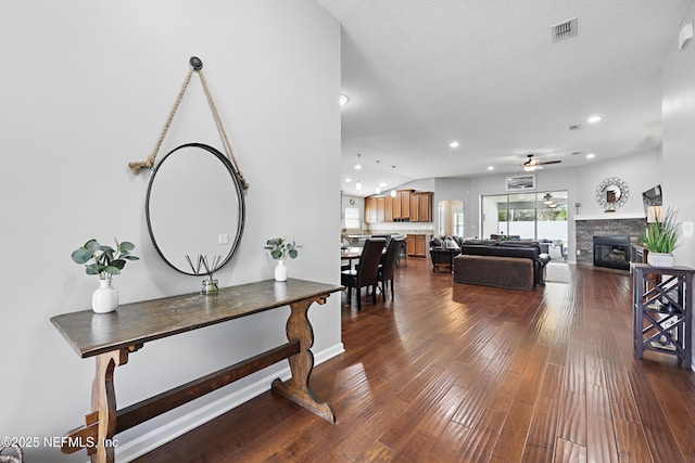 living area with dark wood-style floors, recessed lighting, visible vents, a ceiling fan, and a stone fireplace