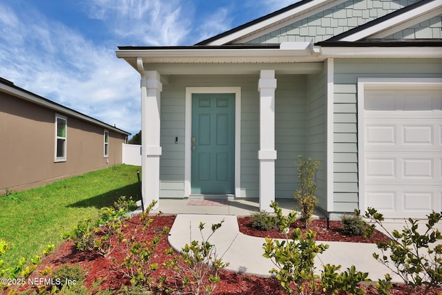 property entrance featuring an attached garage and a yard