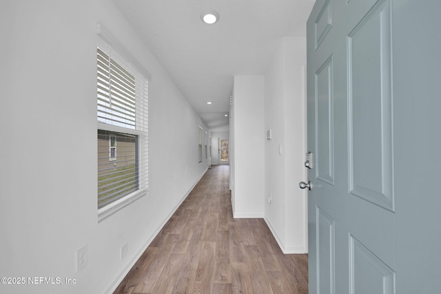 hall with visible vents, baseboards, wood finished floors, and recessed lighting