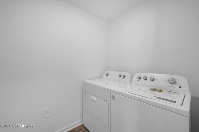 clothes washing area featuring dark wood-type flooring, laundry area, independent washer and dryer, and baseboards