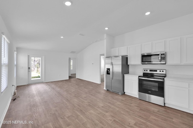 kitchen featuring lofted ceiling, stainless steel appliances, white cabinetry, light countertops, and light wood-type flooring