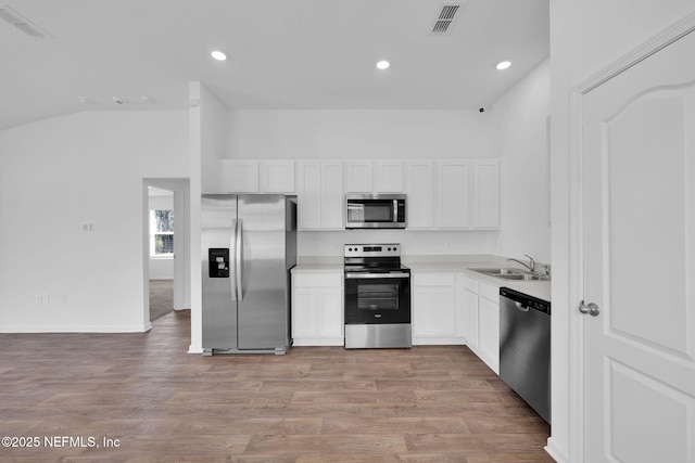 kitchen with stainless steel appliances, visible vents, light wood-style floors, white cabinetry, and a sink