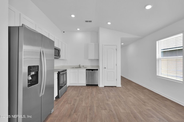 kitchen featuring stainless steel appliances, light countertops, visible vents, white cabinets, and a sink