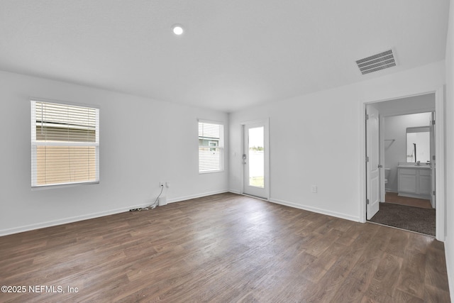 spare room featuring visible vents, baseboards, and wood finished floors