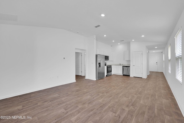 unfurnished living room featuring lofted ceiling, recessed lighting, visible vents, light wood-style floors, and baseboards