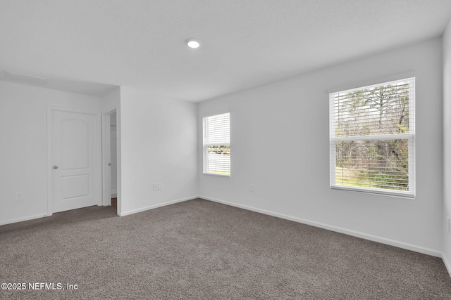 carpeted spare room featuring a textured ceiling and baseboards