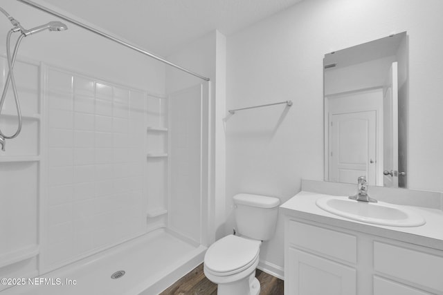 bathroom featuring toilet, a shower stall, vanity, and wood finished floors