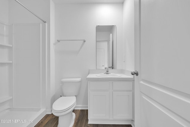 bathroom featuring toilet, wood finished floors, vanity, baseboards, and a shower stall