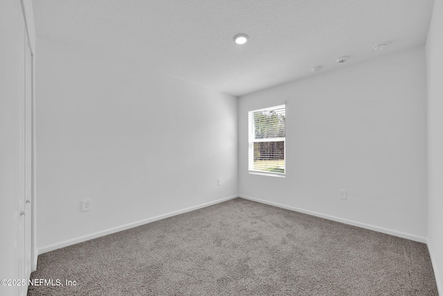 carpeted spare room featuring baseboards and a textured ceiling