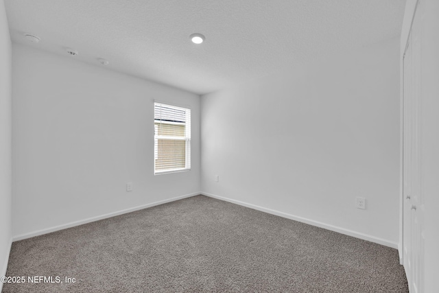 unfurnished room with a textured ceiling, carpet floors, and baseboards