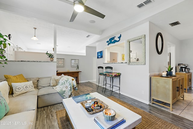 living area with wood finished floors, visible vents, and baseboards