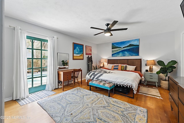 bedroom with baseboards, ceiling fan, wood finished floors, access to exterior, and a textured ceiling