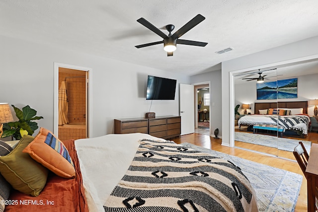 bedroom with a ceiling fan, a textured ceiling, visible vents, and wood finished floors