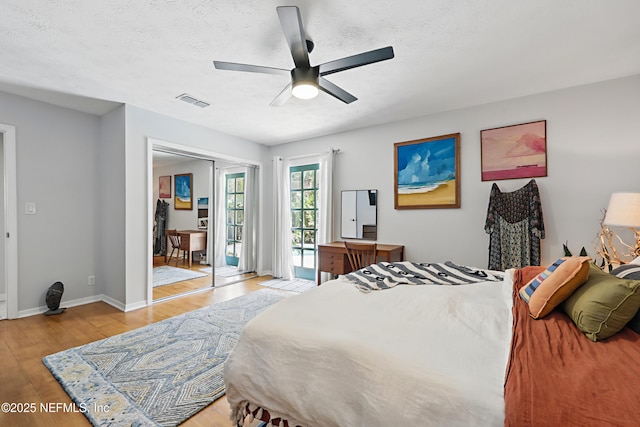 bedroom featuring visible vents, a ceiling fan, a textured ceiling, light wood-type flooring, and baseboards