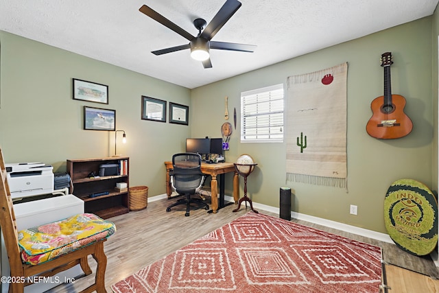 office featuring a textured ceiling, wood finished floors, a ceiling fan, and baseboards