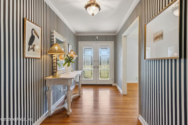 foyer featuring french doors, crown molding, wood finished floors, baseboards, and wallpapered walls