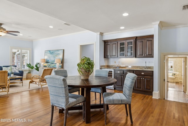 dining room with light wood-style flooring, indoor wet bar, visible vents, and recessed lighting