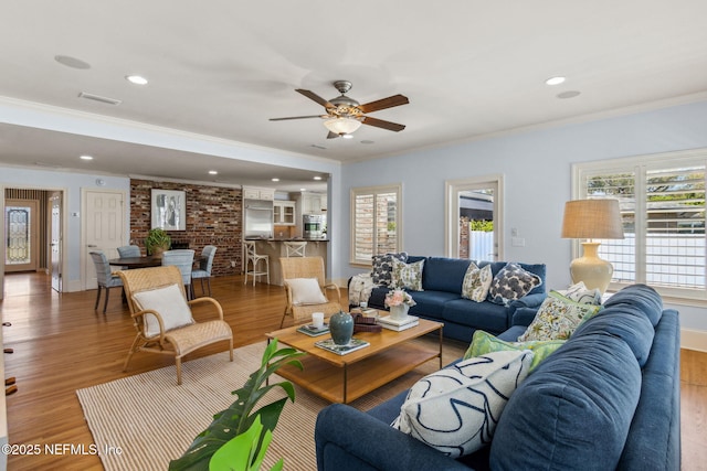 living room with light wood-type flooring, ceiling fan, ornamental molding, and recessed lighting