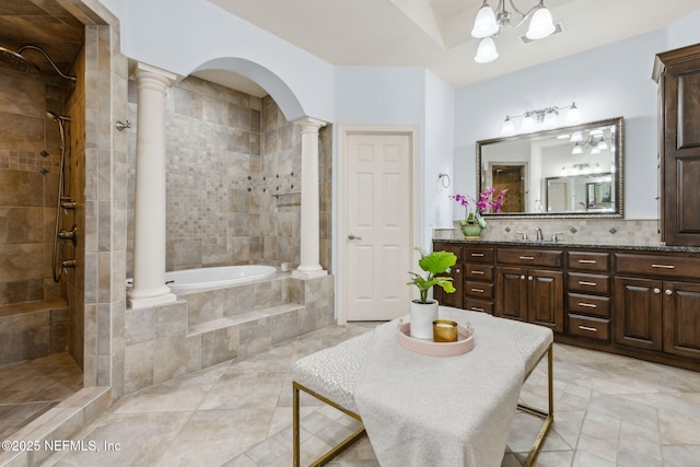 bathroom featuring tiled bath, tiled shower, vanity, ornate columns, and a notable chandelier