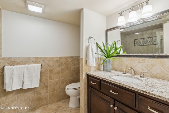 full bathroom featuring tile walls, toilet, a tile shower, vanity, and tile patterned flooring