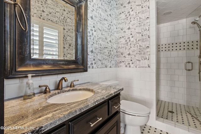 full bathroom featuring a wainscoted wall, tile walls, toilet, a shower stall, and vanity