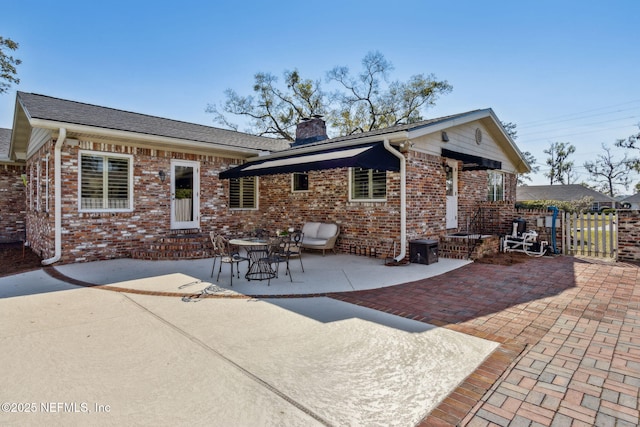 back of house with brick siding, a chimney, entry steps, a patio area, and fence