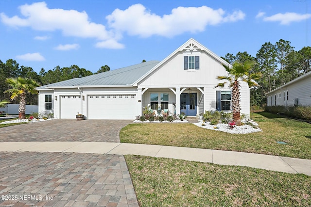 view of front of home with decorative driveway, a porch, metal roof, a garage, and a front lawn