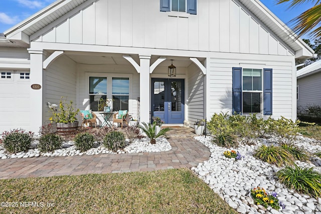 view of exterior entry with board and batten siding, covered porch, and a garage