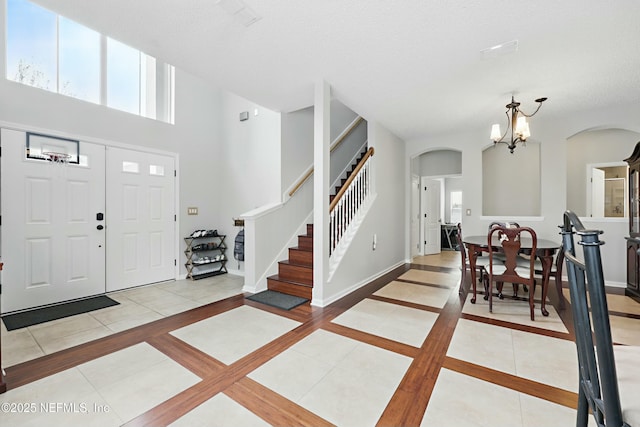 entrance foyer featuring arched walkways, an inviting chandelier, tile patterned flooring, and baseboards