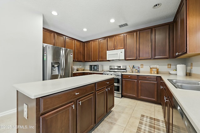 kitchen with light tile patterned floors, light countertops, visible vents, appliances with stainless steel finishes, and a kitchen island