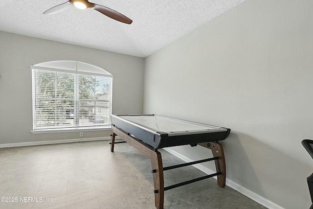 recreation room featuring ceiling fan, baseboards, and a textured ceiling