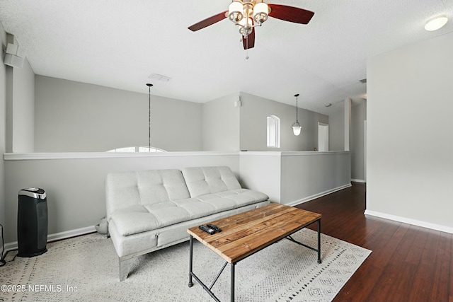 living room with visible vents, a textured ceiling, baseboards, and wood finished floors